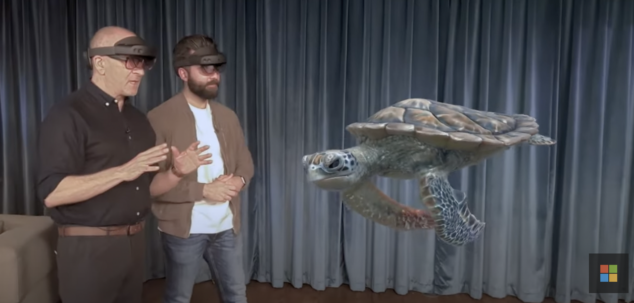 two people wearing HoloLens 2 devices in a demo looking at 3D sea turtle